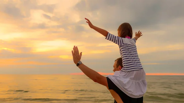 Child on dad's shoulders on the background of the setting sun — Stock Photo, Image