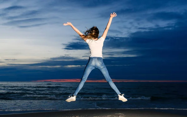 Teenage girl jumping on the beach at dusk time — Stock Photo, Image