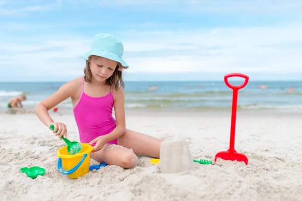 Mutlu çocuk kız yaz aylarında plajda kum ile oynarken — Stok fotoğraf