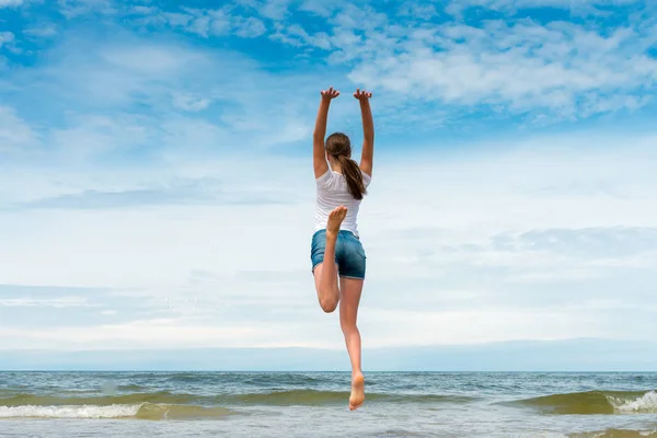 Happy girl jumping on the beach at day time — Stock Photo, Image