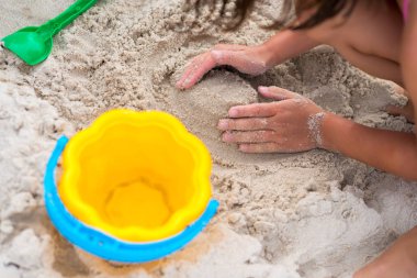 Mutlu çocuk yazın kumsalda kumla oynuyor.