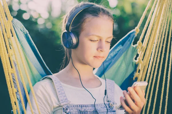 Giovane ragazza che ascolta musica con le cuffie sdraiato su un'amaca — Foto Stock