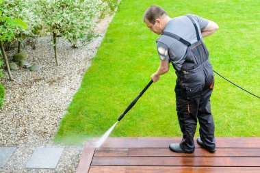 Elektrik yıkama - teras temizleyicisi ile adam temizleme - ahşap teras yüzeyinde yüksek su basıncı temizleyici