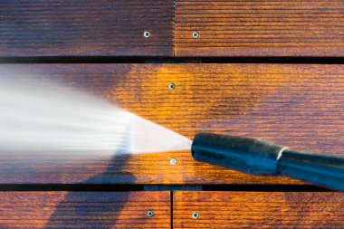 Terası elektrikli çamaşır makinesiyle temizliyor. Tahta teras yüzeyindeki yüksek su basıncı temizleyicisi.