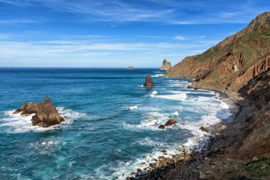 Siyah volkanik kumsal - Beniho, okyanus dalgaları pürüzsüz kıyıya akıyor, okyanustaki büyük kayalıklar