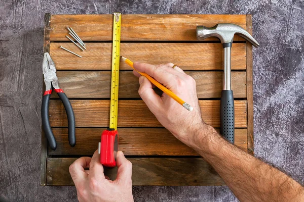 Medições usando tamanhos de roleta para reparo. Mãos com a ferramenta. Conjunto de ferramentas para reparo doméstico. Martelo, alicate, pregos, nozes . — Fotografia de Stock
