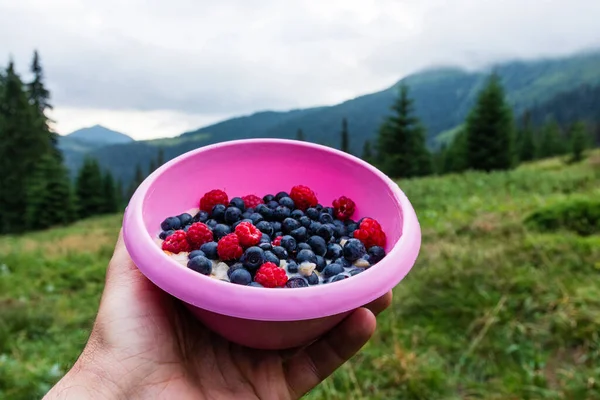 Oatmeal with blueberries and raspberries in a campsite — Stock Photo, Image