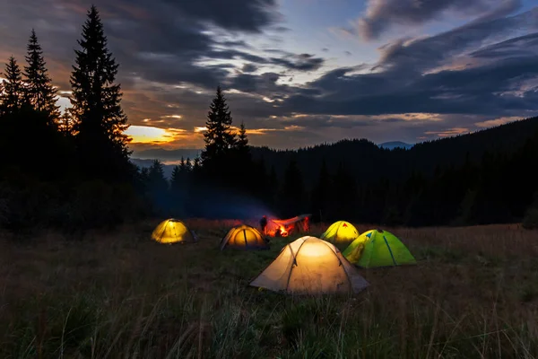 Noche en los Cárpatos Ucranianos. Tiendas que brillan en el césped sobre un fondo de puesta de sol. Camping en las montañas. — Foto de Stock