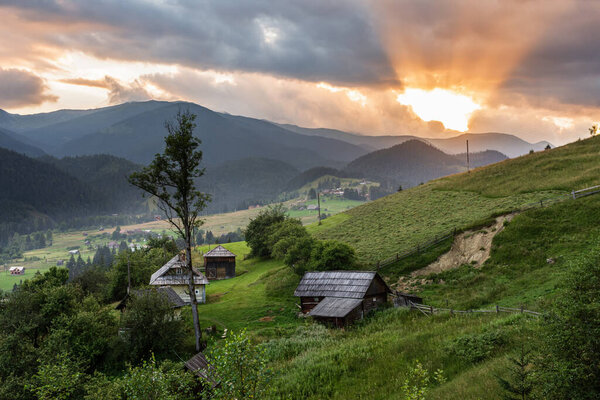 Sunset in a mountain village in the Ukrainian Carpathians. Green mountain slopes and orange rays of the setting sun., Ukraine, Europe.