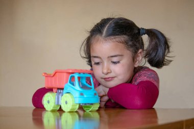 Beyaz kız oyuncak kamyonla oynuyor.