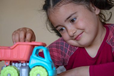 Beyaz kız oyuncak kamyonla oynuyor.