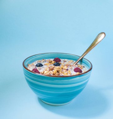 Kahvaltı için sağlıklı müsli çilek ve süt, müsli, Mısır kase. Üzerinde mavi arka plan.