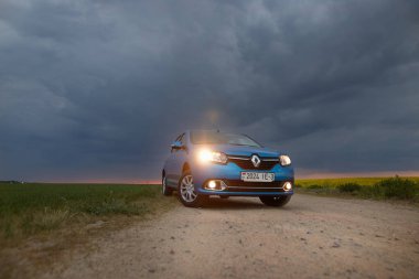 Gomel, Belarus - 15 Mayıs 2018: fırtınalı gökyüzü karşı alanındaki Park Reno Logan mavi araba