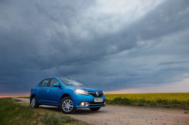 Gomel, Belarus - 15 Mayıs 2018: fırtınalı gökyüzü karşı alanındaki Park Reno Logan mavi araba