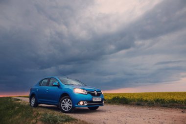Gomel, Belarus - 15 Mayıs 2018: fırtınalı gökyüzü karşı alanındaki Park Reno Logan mavi araba