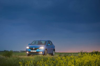 Gomel, Belarus - 15 Mayıs 2018: fırtınalı gökyüzü karşı alanındaki Park Reno Logan mavi araba