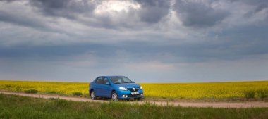 Gomel, Belarus - 15 Mayıs 2018: fırtınalı gökyüzü karşı alanındaki Park Reno Logan mavi araba