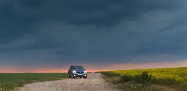 Gomel, Belarus - 15 Mayıs 2018: fırtınalı gökyüzü karşı alanındaki Park Reno Logan mavi araba