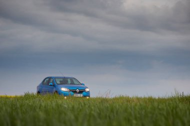 Gomel, Belarus - 15 Mayıs 2018: fırtınalı gökyüzü karşı alanındaki Park Reno Logan mavi araba