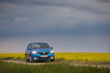 Gomel, Belarus - 15 Mayıs 2018: fırtınalı gökyüzü karşı alanındaki Park Reno Logan mavi araba