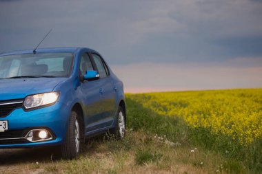Gomel, Belarus - 15 Mayıs 2018: fırtınalı gökyüzü karşı alanındaki Park Reno Logan mavi araba