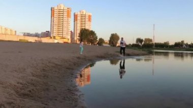 adam ve kız mutlu plaj boyunca akşam çalışan.