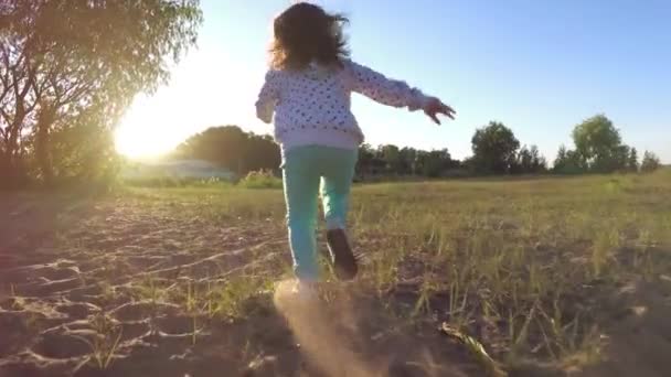 Flickan glatt kör genom fältet på kvällen. — Stockvideo