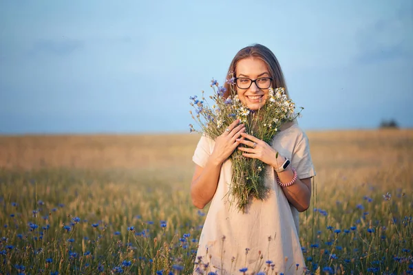 girl with a bouquet of daisies and cornflowers in the field