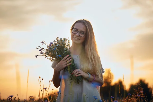 ヒナギクとフィールドのヤグルマギクの花束を持つ少女 — ストック写真
