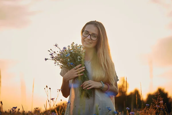 ヒナギクとフィールドのヤグルマギクの花束を持つ少女 — ストック写真