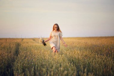 Çiçekli kız tahıl tarlasında yürüyor