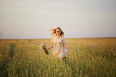 Çiçekli kız tahıl tarlasında yürüyor