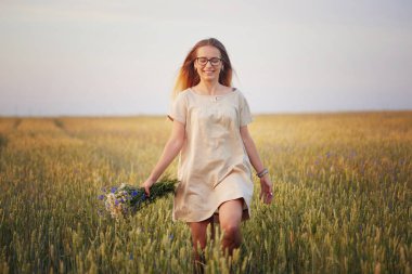 Çiçekli kız tahıl tarlasında yürüyor