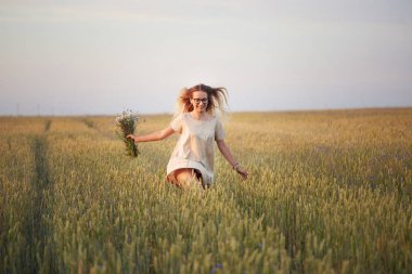 Çiçekli kız tahıl tarlasında yürüyor