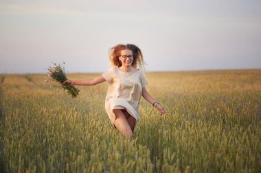 Çiçekli kız tahıl tarlasında yürüyor