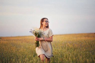 Çiçekli kız tahıl tarlasında yürüyor