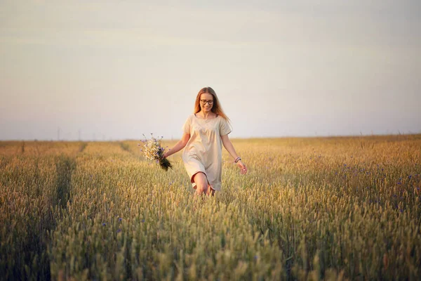 Çiçekli kız tahıl tarlasında yürüyor