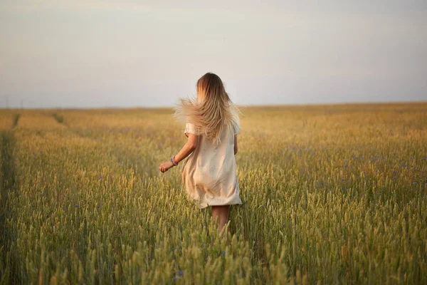 Çiçekli kız tahıl tarlasında yürüyor