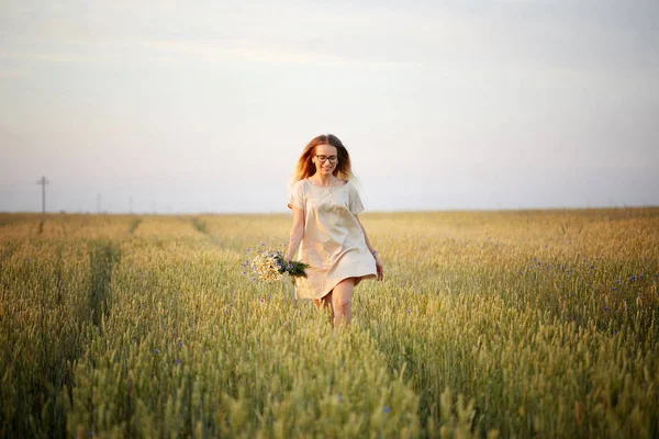 Çiçekli kız tahıl tarlasında yürüyor