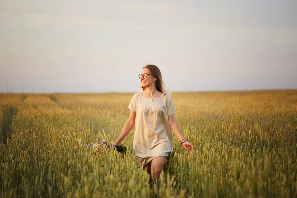 Çiçekli kız tahıl tarlasında yürüyor