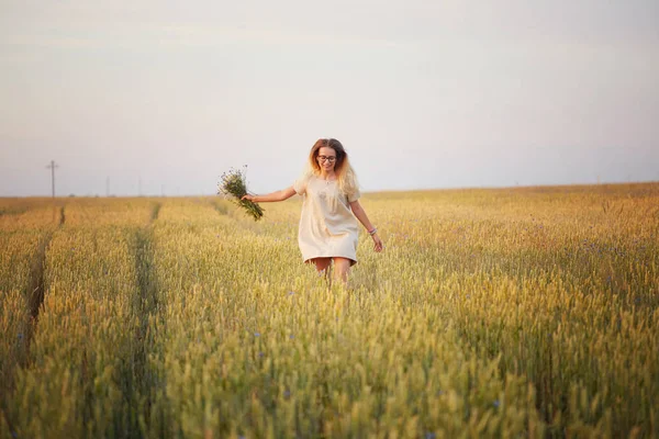 Çiçekli kız tahıl tarlasında yürüyor