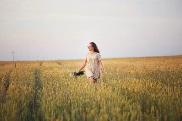 Çiçekli kız tahıl tarlasında yürüyor