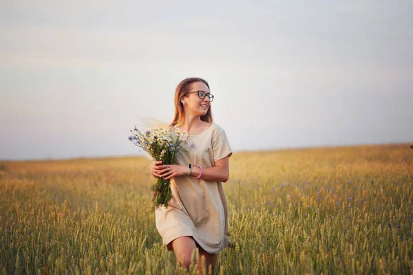 Çiçekli kız tahıl tarlasında yürüyor