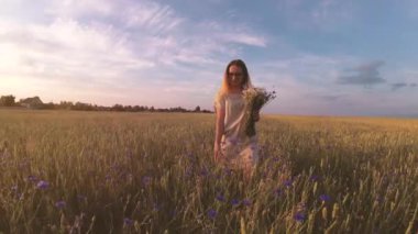 Çiçekli kız tahıl tarlasında yürüyor.