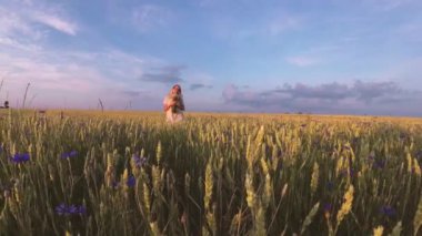 Çiçekli kız tahıl tarlasında yürüyor.