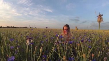 Çiçekli kız tahıl tarlasında yürüyor.