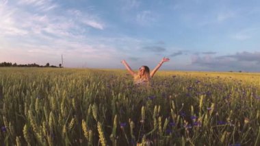 Çiçekli kız tahıl tarlasında yürüyor.