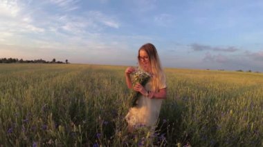 Çiçekli kız tahıl tarlasında yürüyor.