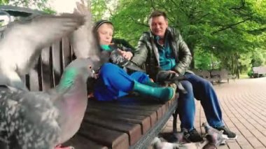 Gomel, Belarus. Baba ve oğul parkta vahşi güvercin beslenen.
