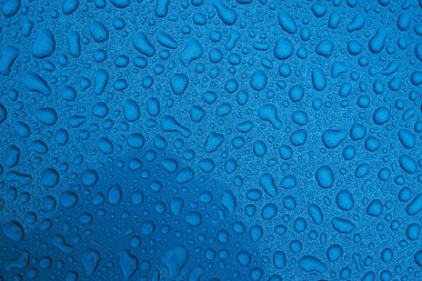 Mavi pürüzsüz bir yüzey üzerinde yağmur damlaları